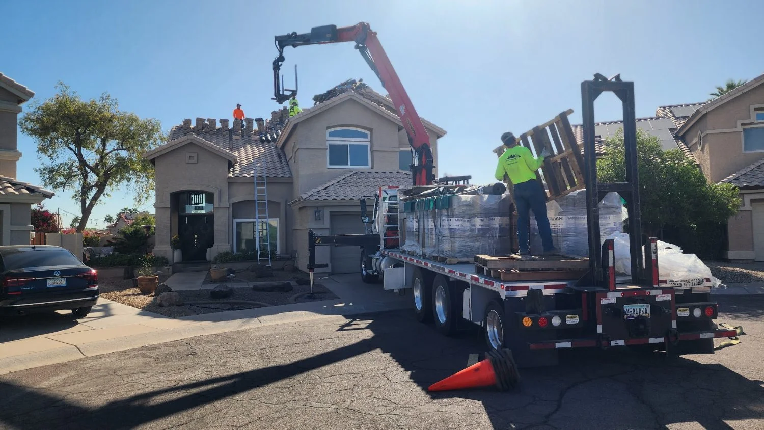 Boom truck delivering roof tile to a two-story home